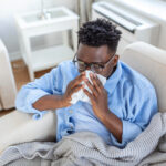 A young man experiencing flu symptoms, taking rest at home.