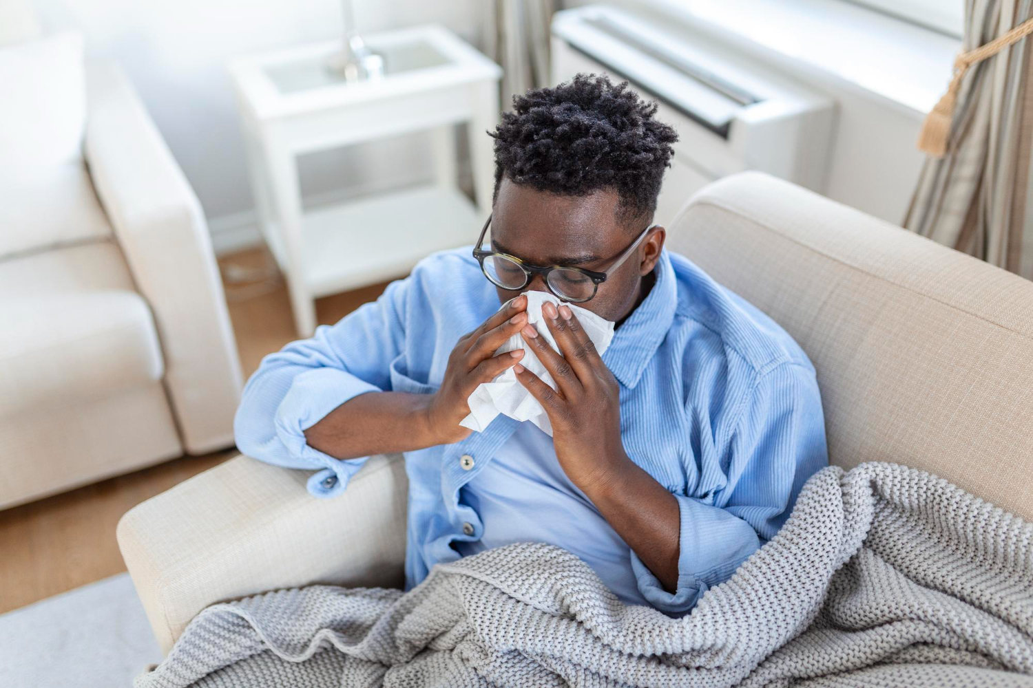 A young man experiencing flu symptoms, taking rest at home.