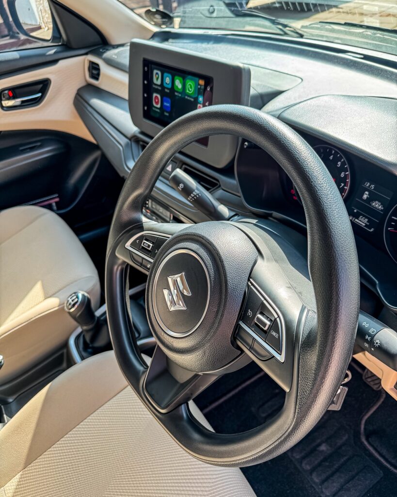 Inside the DZire: A modern cabin featuring a 7-inch infotainment system, digital air controls, and USB ports for convenient everyday driving.