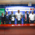 National Commissioner of Police Mr Manoma Vusi Masango and IDM Country Director Mr Karabo Baipidi display the signed Memorandum of Understanding alongside senior officials from the Royal Eswatini Police Service and the Institute of Development Management at Police Headquarters in Mbabane.