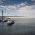 A cargo vessel navigates the waters off Maputo with the iconic Maputo-Katembe Bridge visible in the background