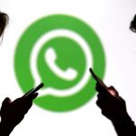 Teenagers pose for a photo while holding smartphones in front of a Whatsapp logo in this illustration taken September 11, 2025. REUTERS/Dado Ruvic/Illustration/File Photo