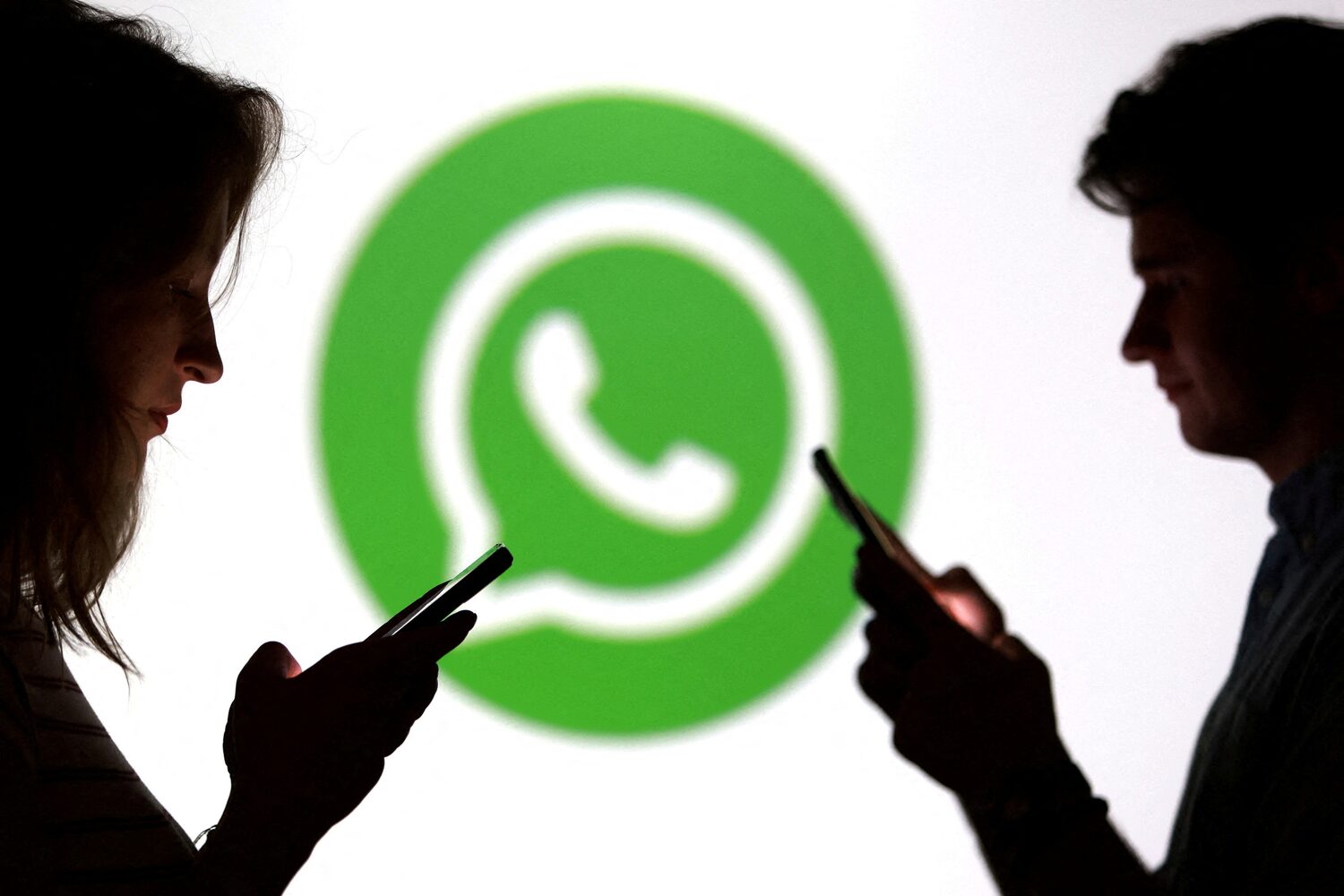 Teenagers pose for a photo while holding smartphones in front of a Whatsapp logo in this illustration taken September 11, 2025. REUTERS/Dado Ruvic/Illustration/File Photo