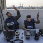 Palestinian journalists attempt to connect to the internet using their phones in Rafah on the southern Gaza Strip on December 27, 2023. Said Khatib / AFP